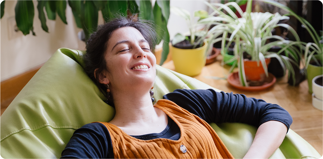 Woman relaxing in a comfortable chair with plants in background